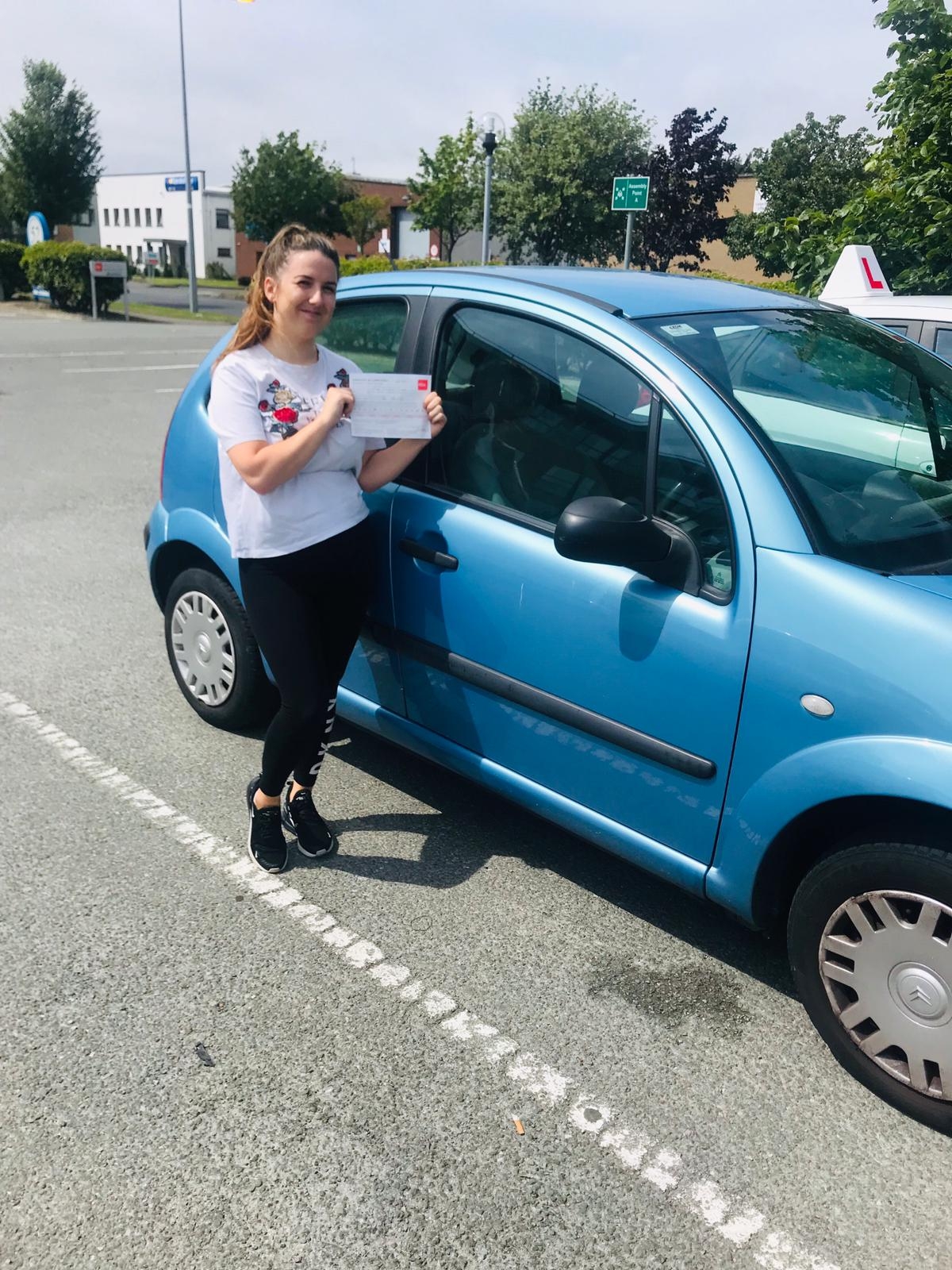 Pupil holding their pass beside the Learn2Drive car